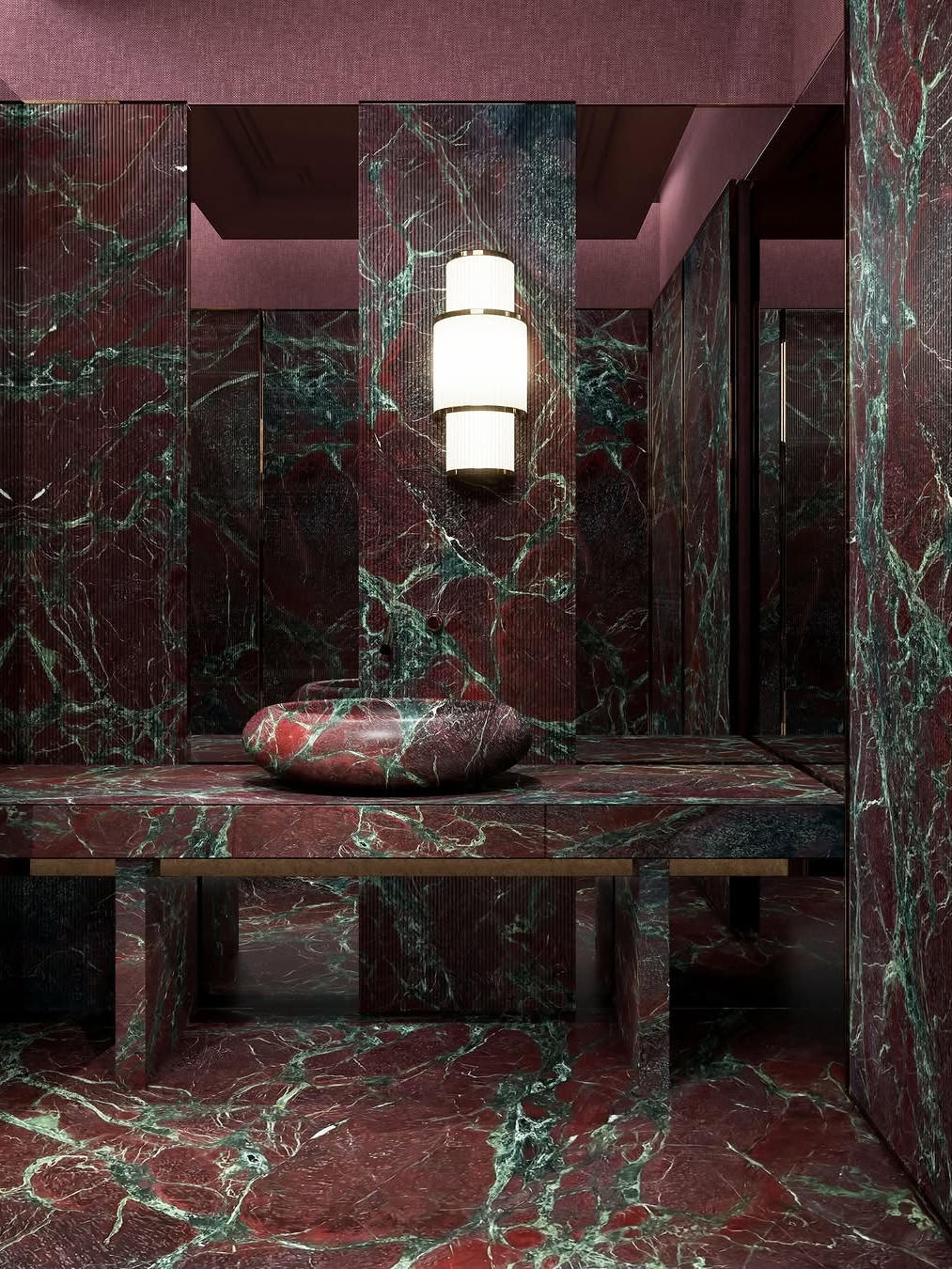 Sculptural bathroom with red and green marble surfaces, statement stone sink and dramatic lighting reflecting luxury interior design trends 2026