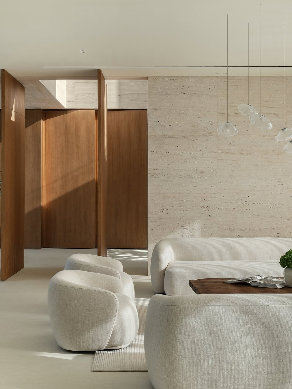Warm minimalist living room with travertine walls, curved boucle sofa, and natural wood paneling